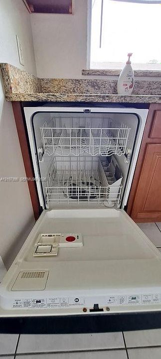 Built-in dishwasher featuring a white interior, multi-level racking system, stone-finish countertop, and medium-tone wood cabinetry