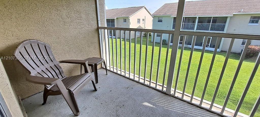 Screened-in balcony featuring stucco walls, concrete flooring, and metal railing