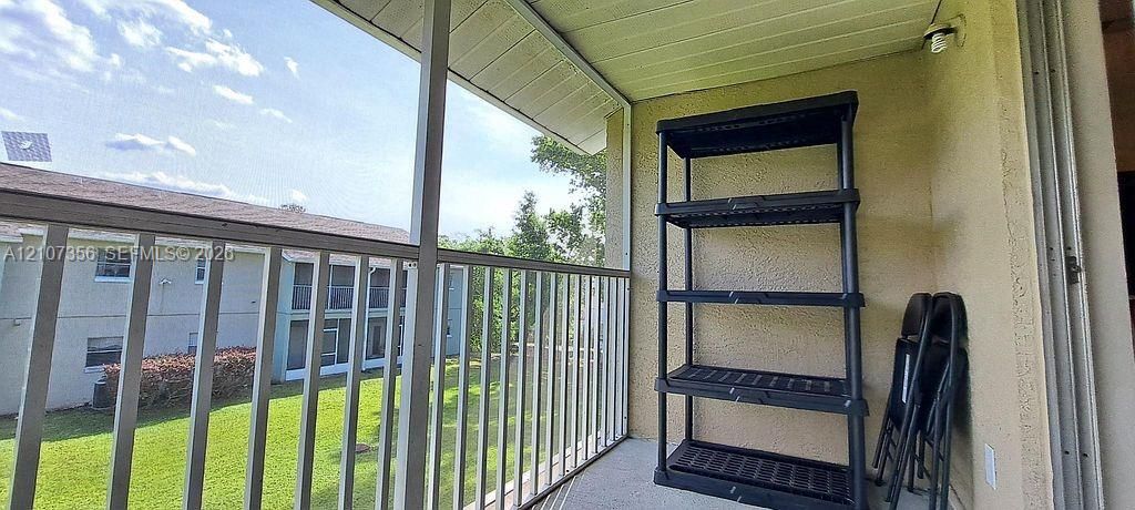 Screened balcony featuring metal railings, stucco walls, and a solid ceiling