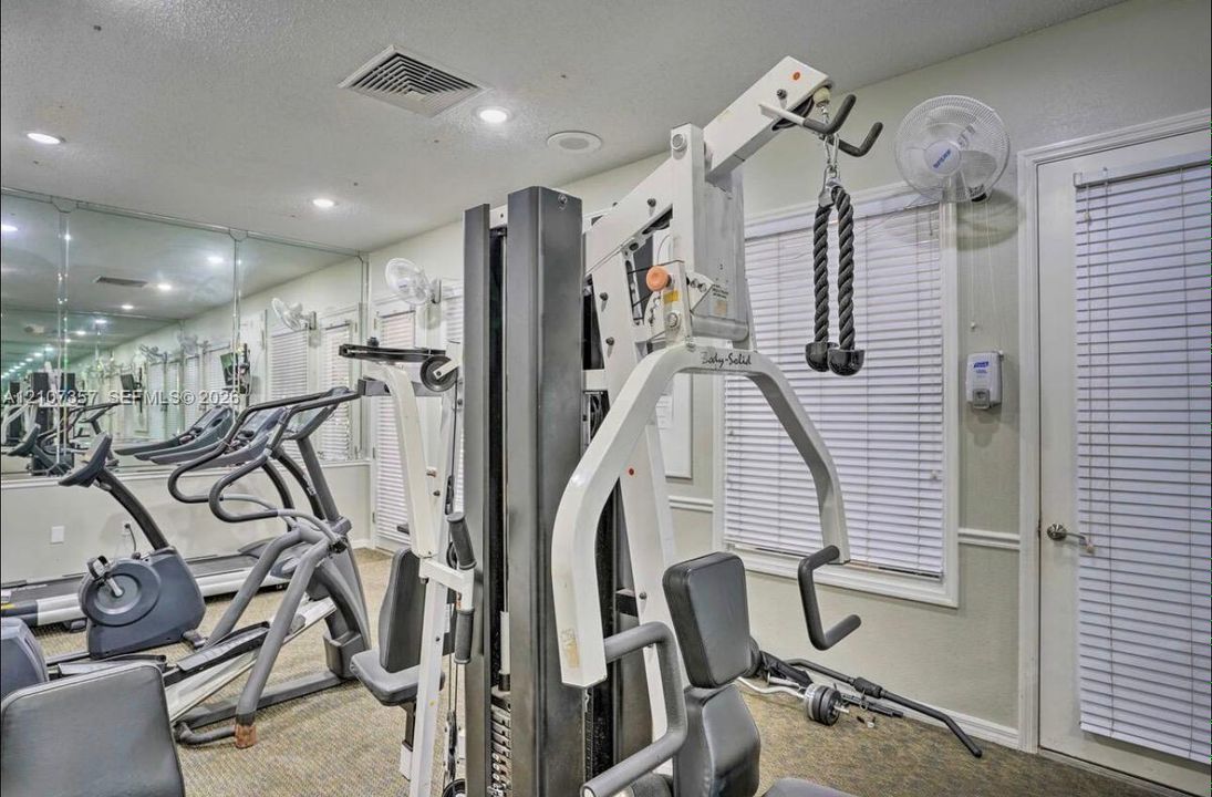 Fitness room featuring floor-to-ceiling mirrors, recessed lighting, and a wall-mounted fan