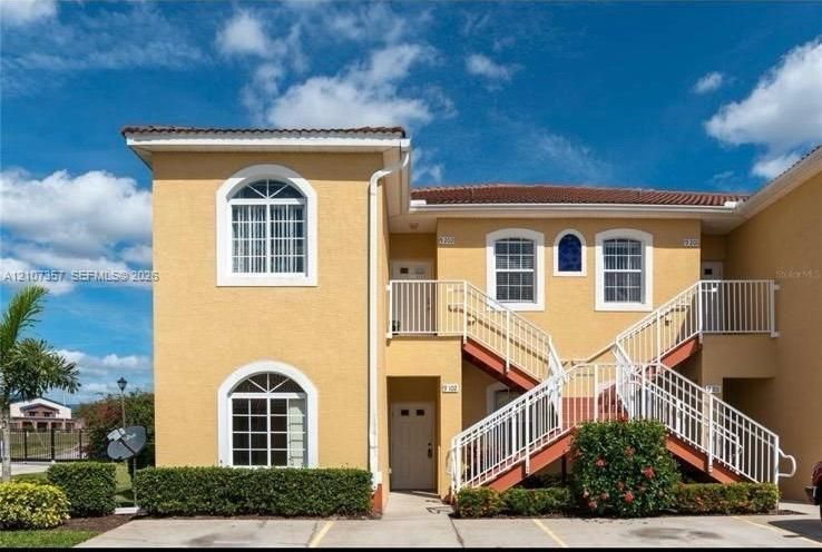 Stucco exterior featuring arched windows, tile roofing, and white metal railings
