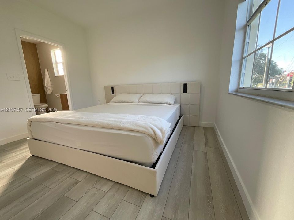 Room featuring wood-finish flooring, a multi-pane window with a stone sill, and a light-toned interior paint palette