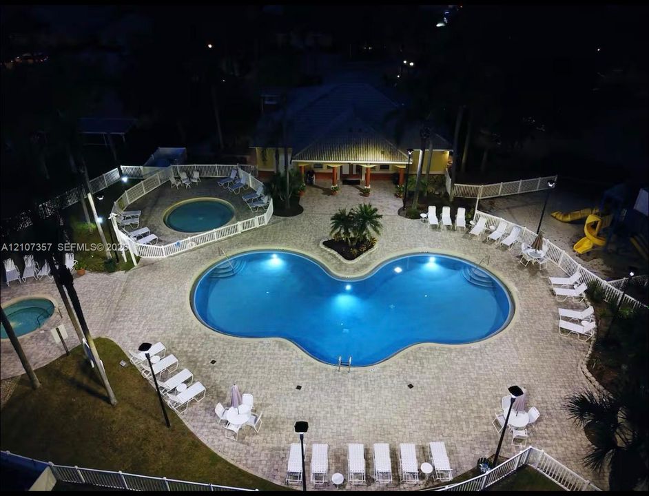Swimming pool complex featuring a curved main pool, two secondary circular pools, paver-stone decking, and perimeter fencing