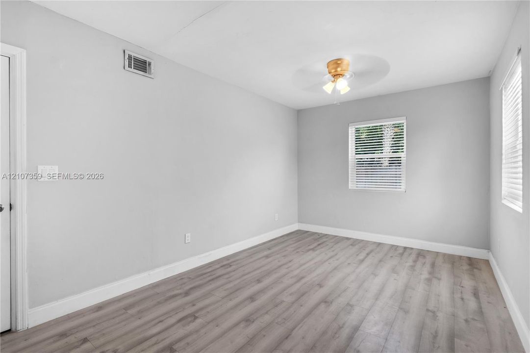 Neutral-toned walls, ceiling-mounted light fixture, and windows featuring horizontal blinds