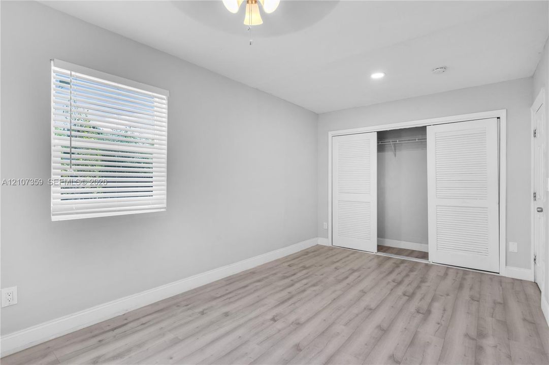 Bedroom with wood-look flooring, natural light, and neutral finishes.