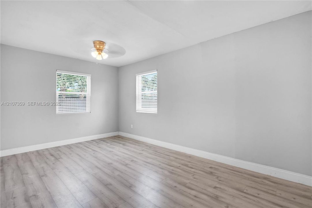 Bright bedroom with multiple windows, neutral finishes, and updated flooring.