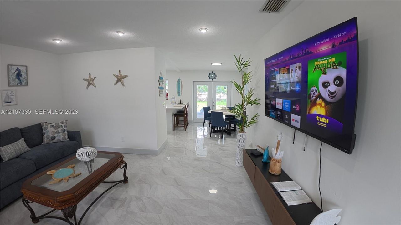 Open-concept interior featuring light-toned tile flooring, recessed ceiling lighting, and double-glass paneled doors