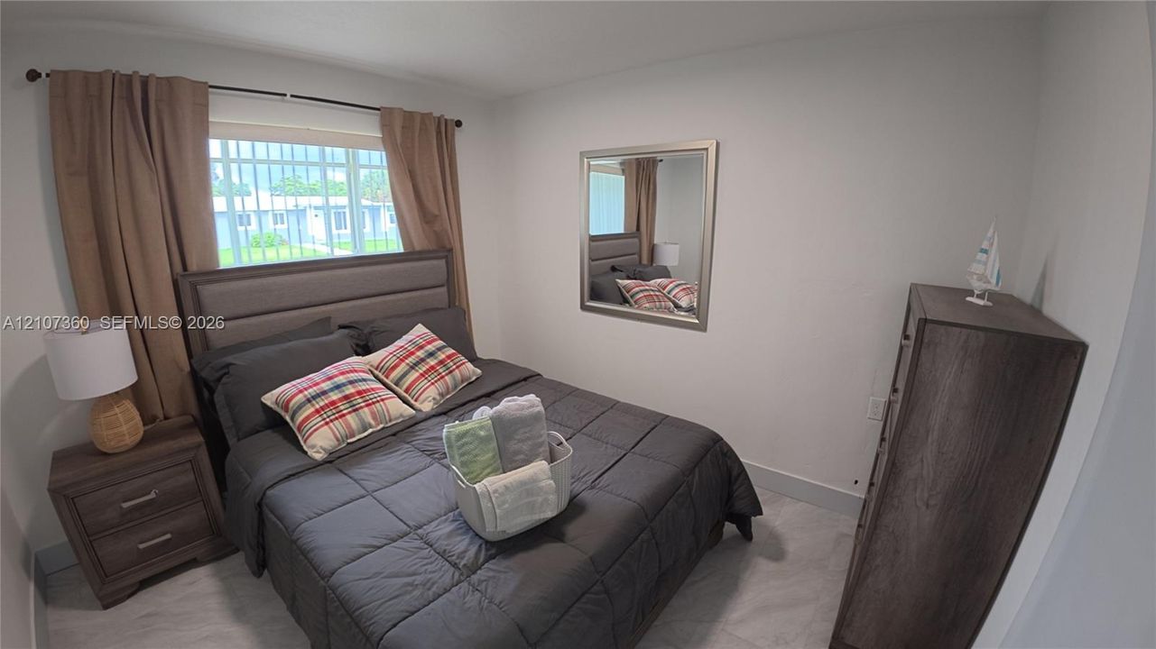 Room featuring neutral-toned walls, light-toned flooring, and a large window with metal security bars