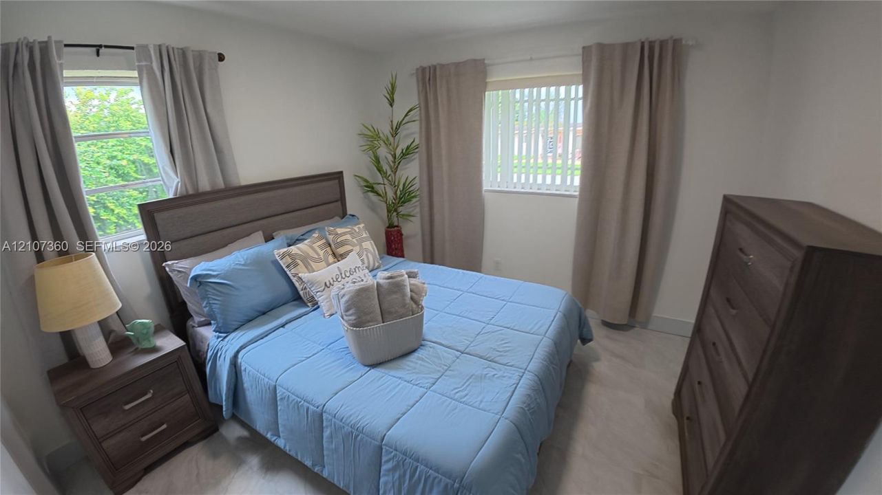 Neutral-toned walls paired with light-colored tile flooring and two windows featuring vertical blinds