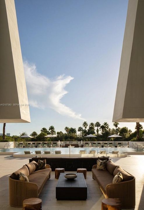 Covered outdoor terrace featuring large-format tile flooring and infinity-edge swimming pool with integrated water features and glass perimeter fencing