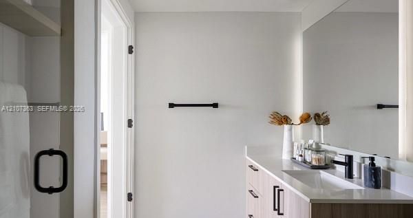 Modern vanity featuring light wood-finish cabinetry, a solid surface countertop, matte black hardware, a wall-to-wall mirror, and a matte black faucet