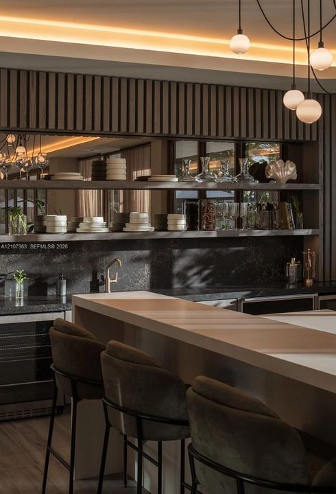 Custom built-in bar featuring a light-toned solid surface countertop, dark stone backsplash, multi-level open shelving, and a mirrored wall panel