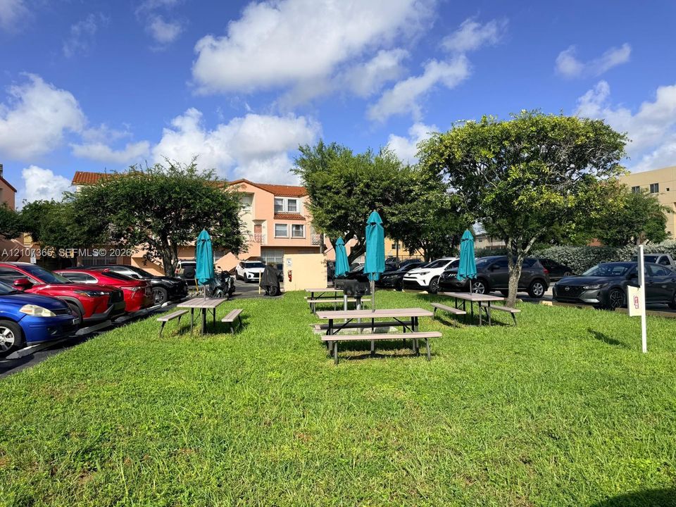 Common area featuring a manicured lawn, mature trees, and designated picnic zones