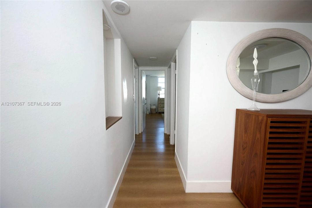 Hallway featuring wood-finish flooring, recessed ceiling lighting, and a built-in wall niche with a wooden shelf