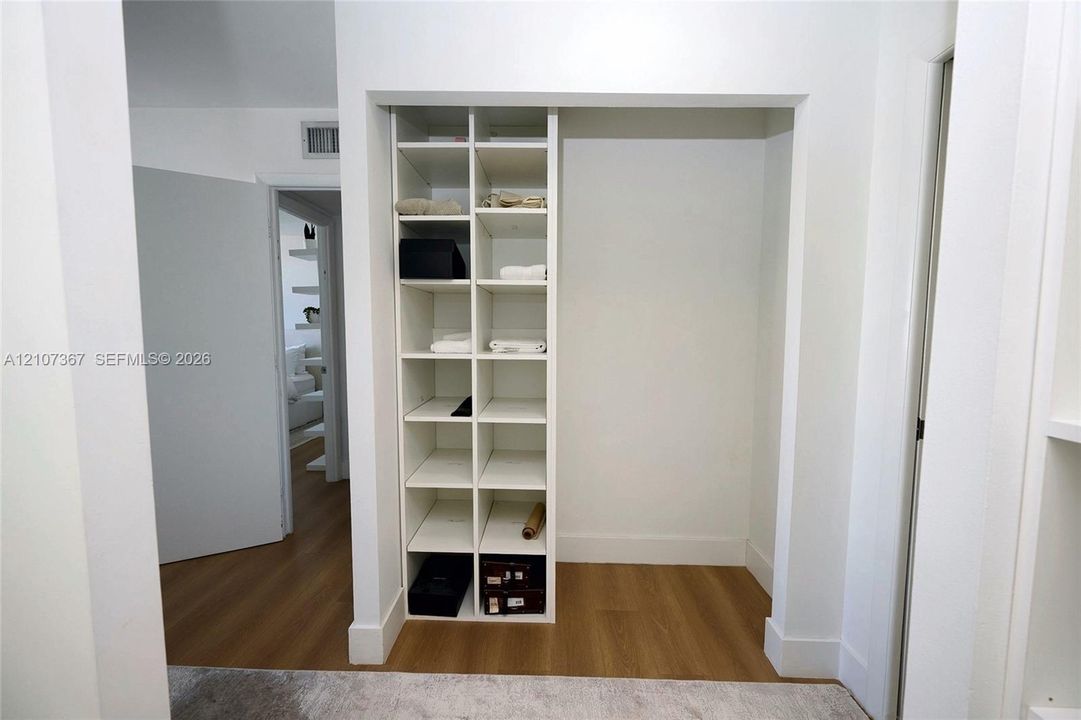 Built-in white shelving unit with multiple open storage compartments and wood-finish flooring