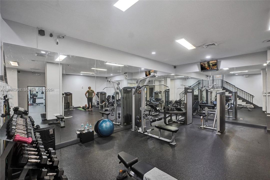 Fitness center featuring wall-to-wall mirrors, recessed lighting, and durable rubberized flooring