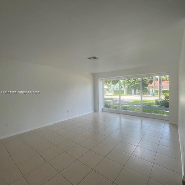 Interior space featuring neutral wall tones, large-format ceramic tile flooring, and a expansive floor-to-ceiling multi-pane window