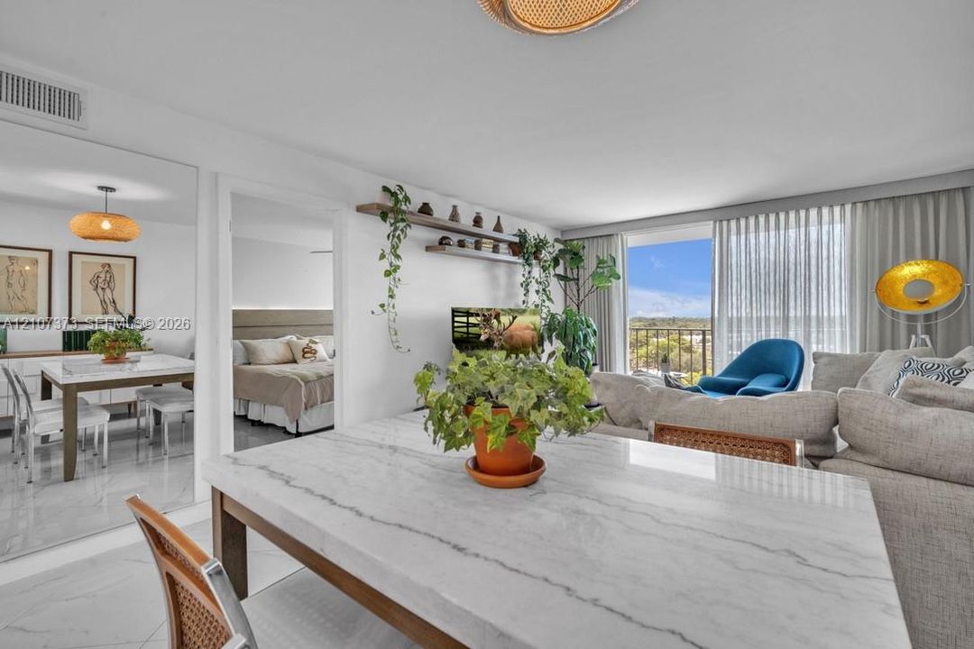 Open-concept interior featuring large-format tile flooring, built-in wall shelving, expansive floor-to-ceiling glass sliding doors, and a full-wall mirror