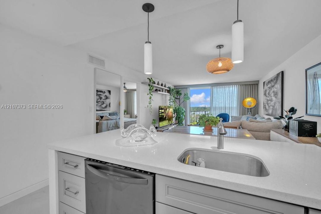 Kitchen featuring a quartz countertop, undermount stainless steel sink, pull-down chrome faucet, shaker-style cabinetry, and integrated stainless steel dishwasher