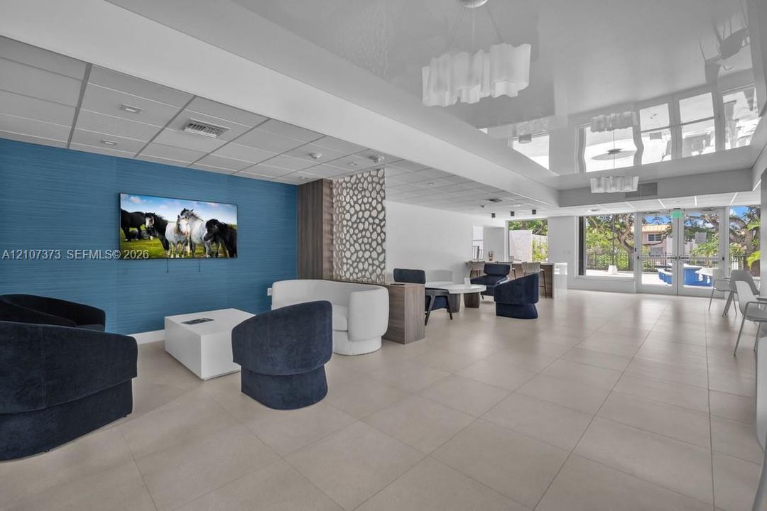 High-gloss ceiling with modern decorative lighting, large-format tile flooring, textured blue accent wall, and intricate lattice privacy screen