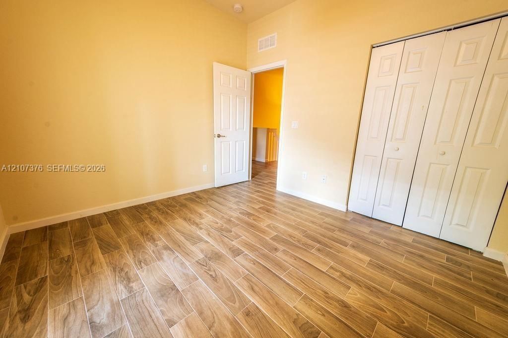 Room featuring wood-finish flooring, white paneled doors, and floor-to-ceiling bifold closet doors