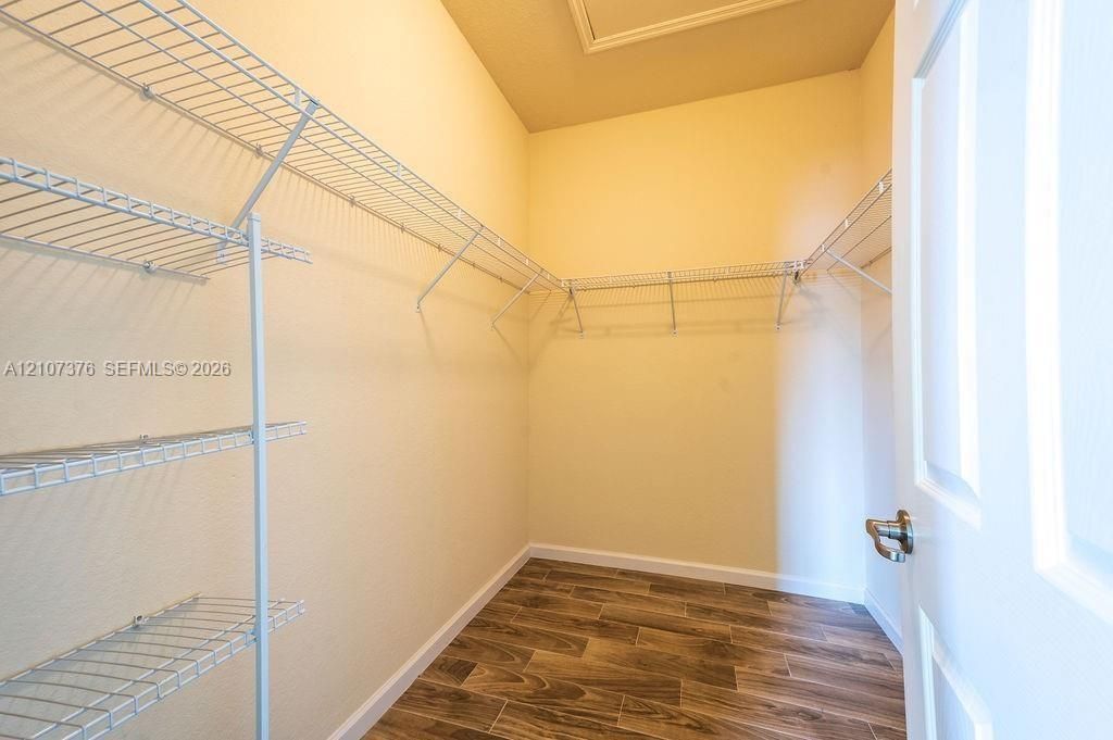 Walk-in closet featuring white wire shelving units and wood-finish tile flooring