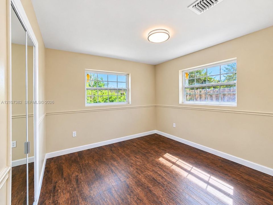 Wood-finish flooring, mirrored sliding closet doors, chair rail molding, and dual grid-pane windows