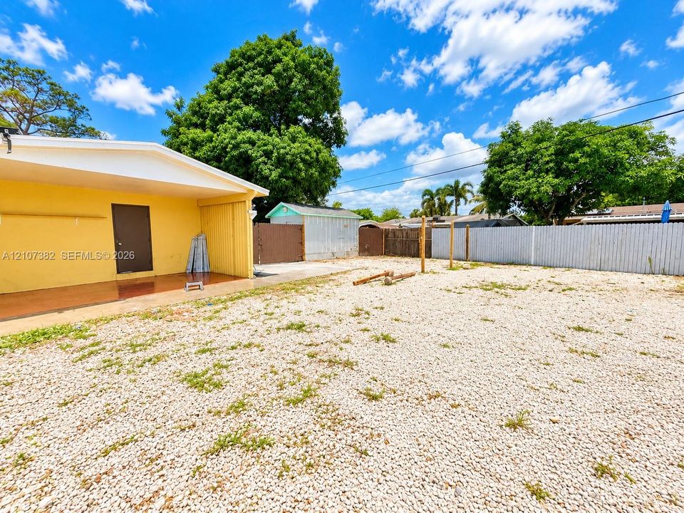 Exterior area featuring a covered patio, gravel ground cover, detached storage shed, and perimeter fencing