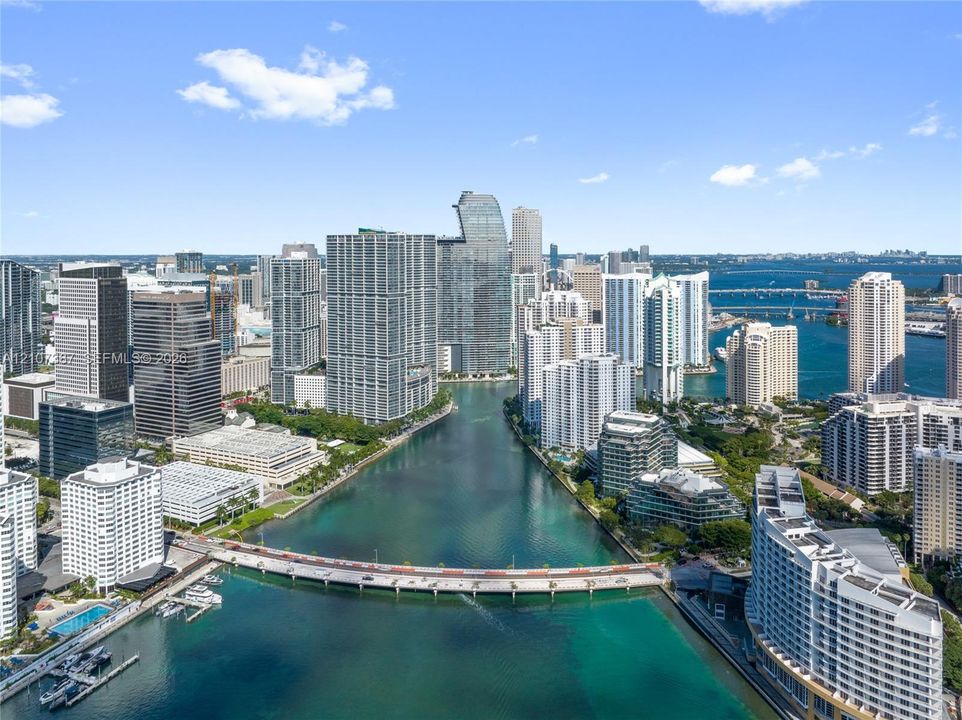 Aerial perspective featuring urban high-rise skyline, waterfront access, marina, and city bridge infrastructure