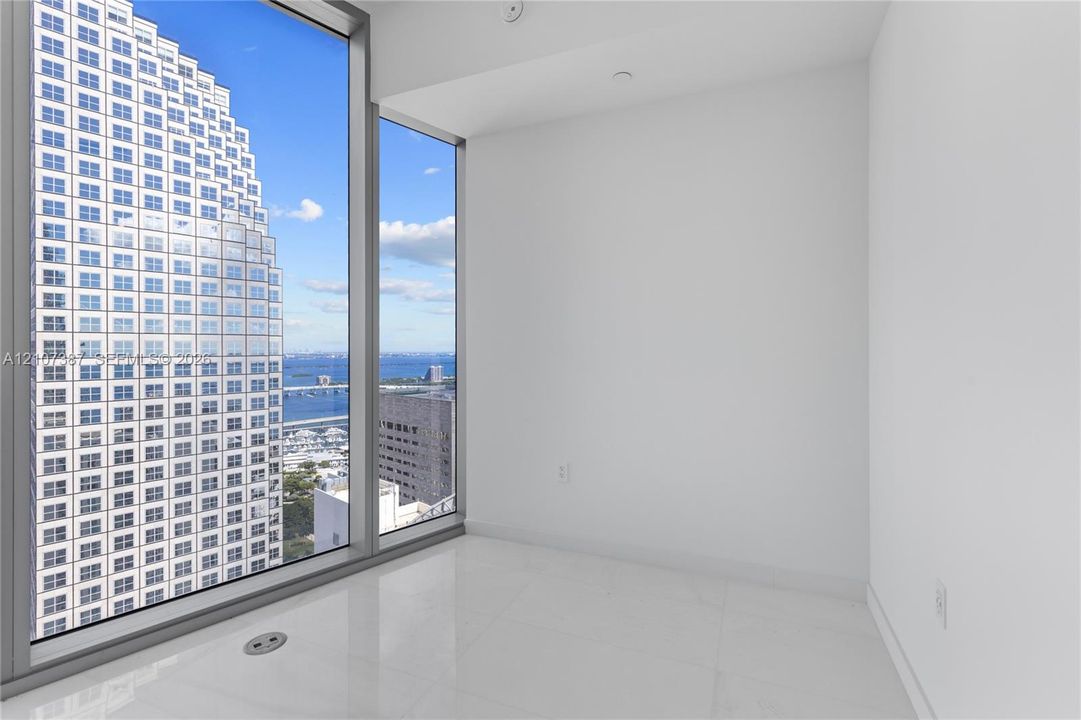 Floor-to-ceiling windows featuring expansive urban and water scenery, complemented by crisp white walls and light-toned tile flooring