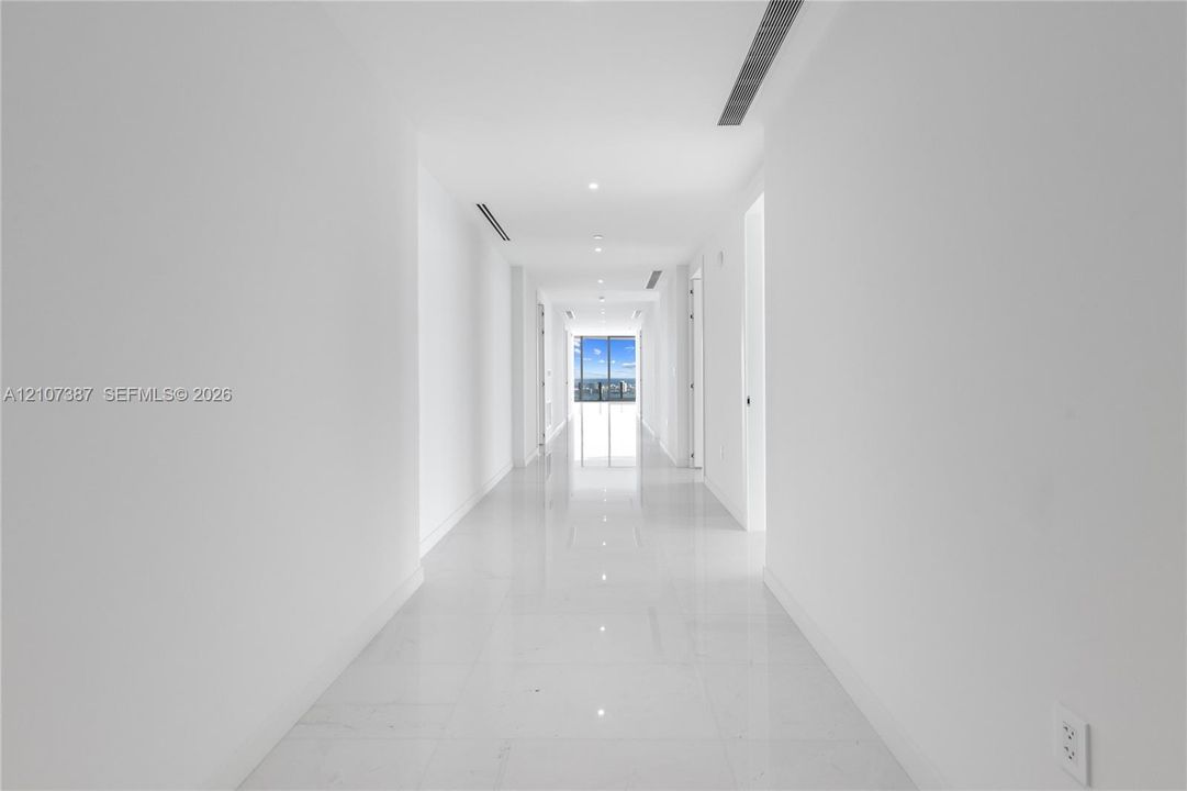 Hallway featuring polished tile flooring, recessed ceiling lighting, and floor-to-ceiling windows