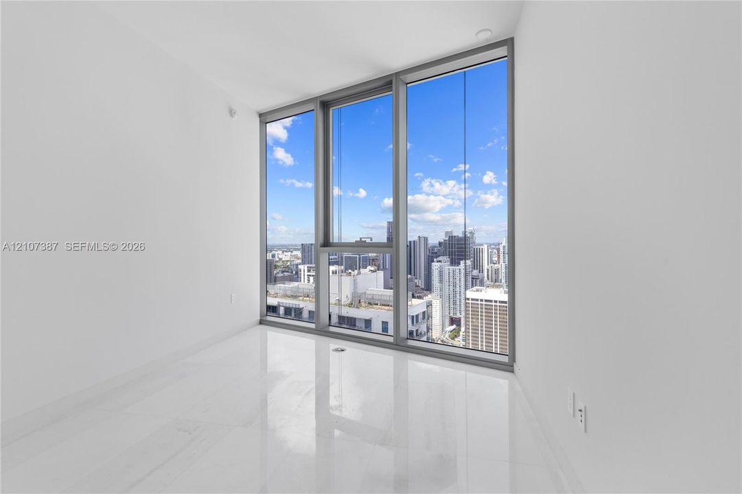 Floor-to-ceiling windows with metal framing, polished light-colored tile flooring, and urban cityscape scenery