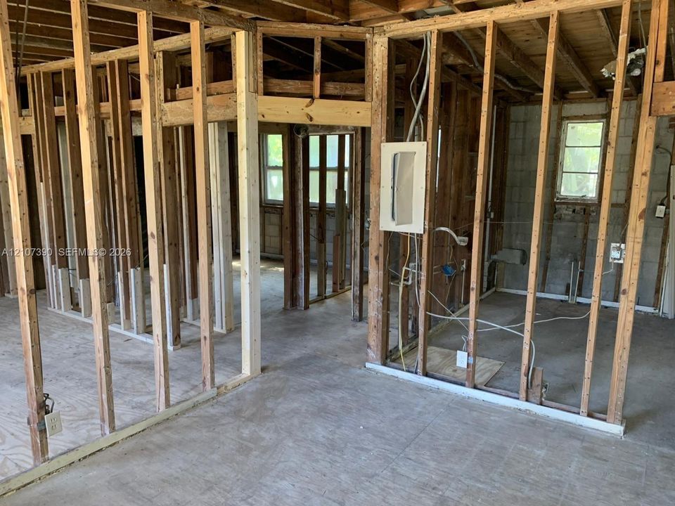 Interior structure featuring exposed wood framing, concrete flooring, and window openings