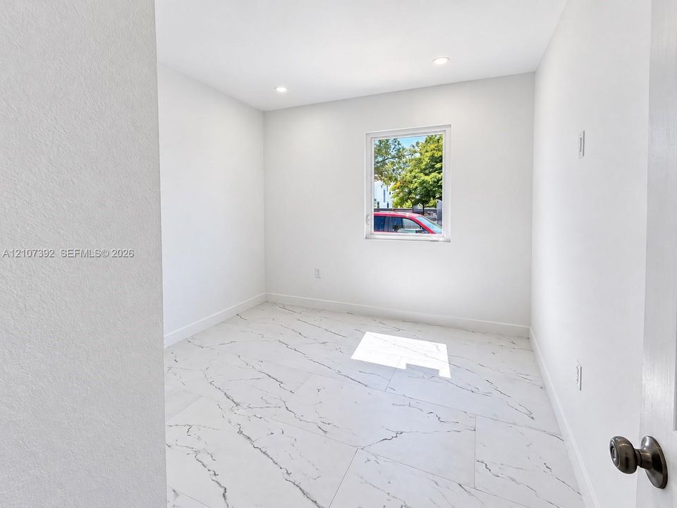 Interior room featuring large-format tile flooring with a veined pattern, recessed ceiling lighting, and a single-pane window