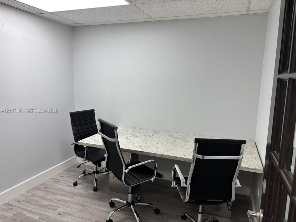 Built-in stone-surface desk, wood-finish flooring, drop-ceiling panels, and French-style door