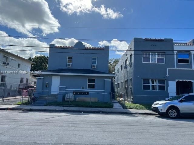 Multi-family exterior featuring a mission-style parapet roofline, stucco facade, and multi-unit address signage