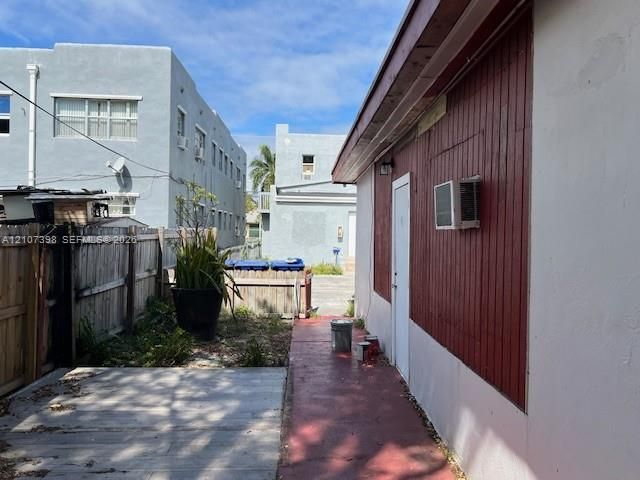 Exterior side yard featuring a concrete walkway, vertical wood siding, and wood-panel fencing