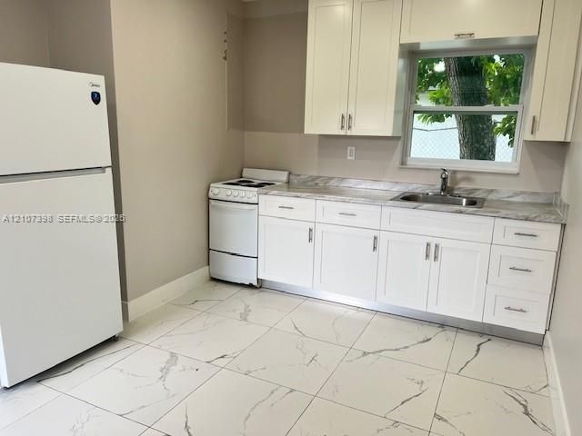 Kitchen featuring white shaker-style cabinetry, stone-finish countertops, stainless steel undermount sink with a gooseneck faucet, and large-format porcelain tile flooring