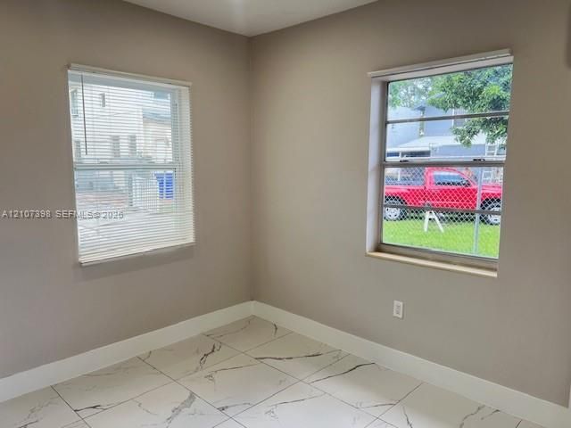 Neutral-toned room featuring large-format tile flooring with a veined pattern and two double-hung windows