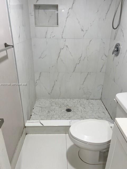 Walk-in shower featuring floor-to-ceiling large-format tile with veining detail, built-in recessed wall niche, and a contrasting hexagonal tile shower floor