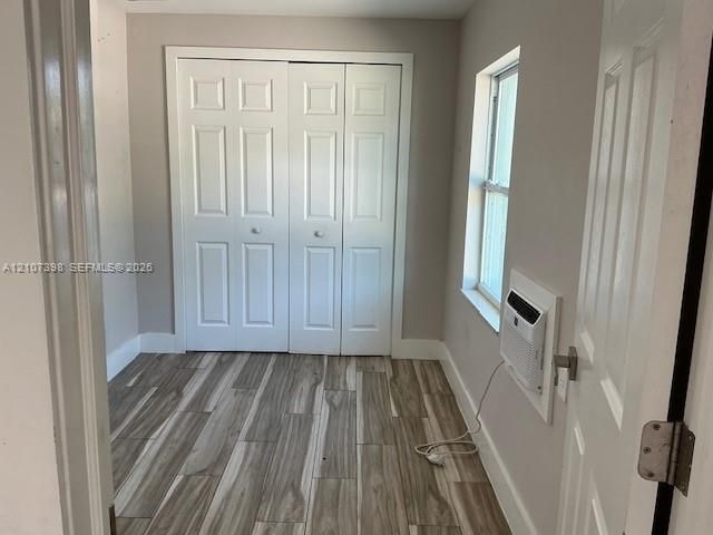 Room featuring wood-finish tile flooring, a multi-panel closet with dual doors, and an inset window