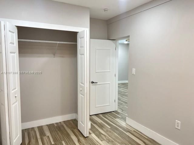 Neutral-toned interior featuring wood-finish flooring, white panel doors, and a closet with integrated wire shelving