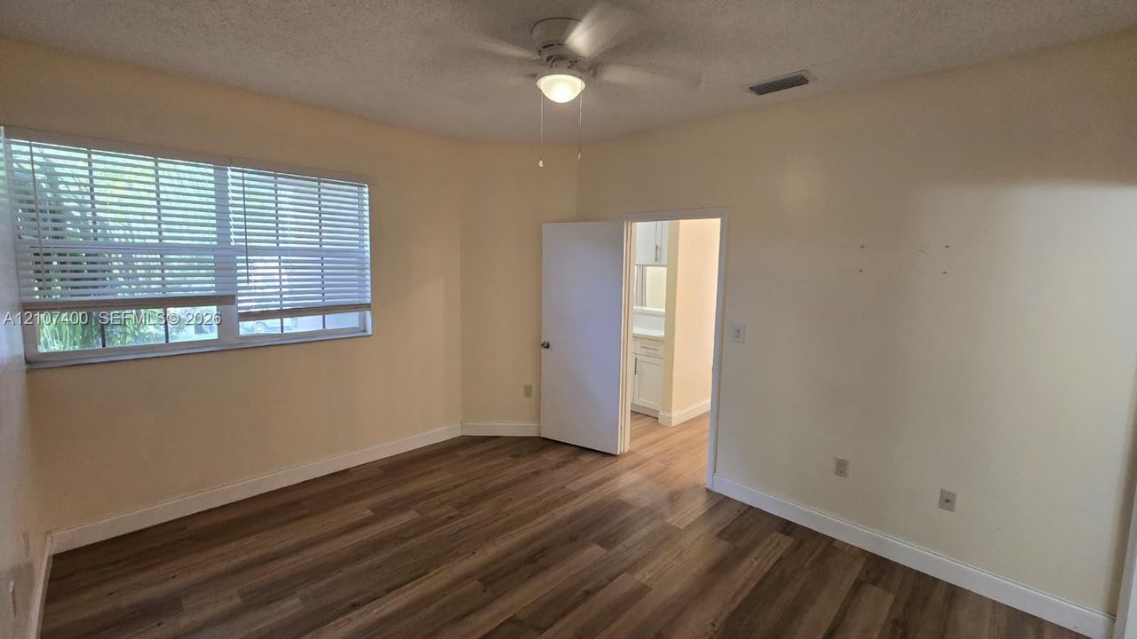 Room featuring wood-finish flooring, a ceiling fan with integrated lighting, and horizontal window blinds
