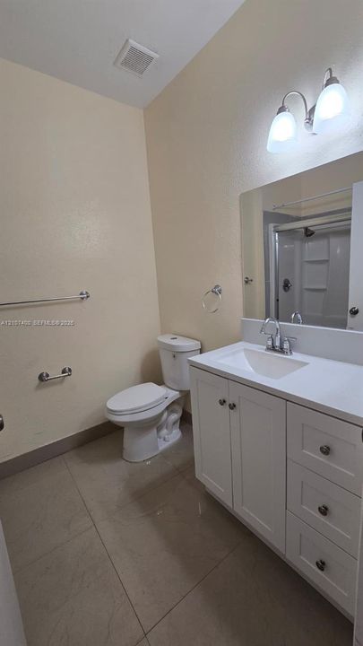 Bathroom featuring a white vanity cabinet with drawers, integrated sink, polished chrome faucet, large wall-mounted mirror, and tile flooring