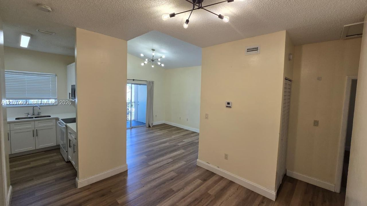 Wood-finish flooring, white cabinetry, minimalist modern multi-arm chandeliers, and sliding glass doors