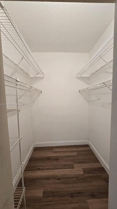 Storage space featuring white wire shelving units and wood-finish flooring