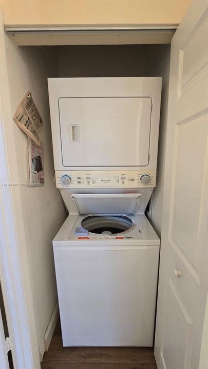 Stacked white washer and dryer unit located within a closet space