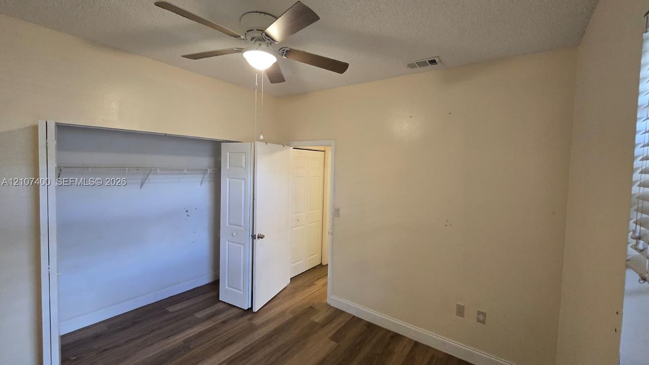 Wood-finish flooring, ceiling fan with integrated light fixture, and closet with white paneled doors