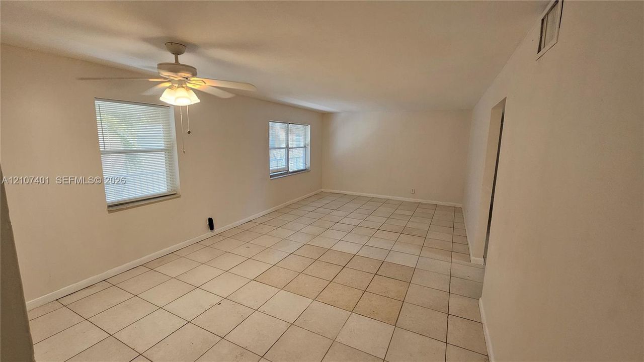 Interior space featuring ceramic tile flooring, neutral wall paint, and a ceiling fan with integrated lighting