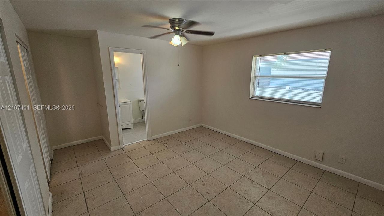 Interior space featuring neutral wall paint, tile flooring, a multi-blade ceiling fan with integrated lighting, and a single-pane window